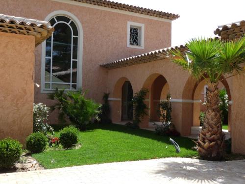 a house with a green yard with a palm tree at "AU HAVRE DE PAIX" 5 étoiles Prestige jacuzzi, hammam, sauna, PISCINE chauffée Mougins Cannes Grasse in Mougins