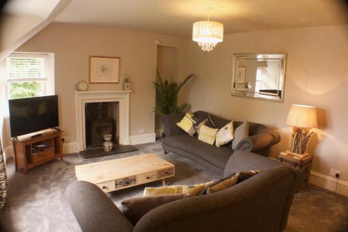 a living room with couches and a table and a tv at The Apartment in Portree