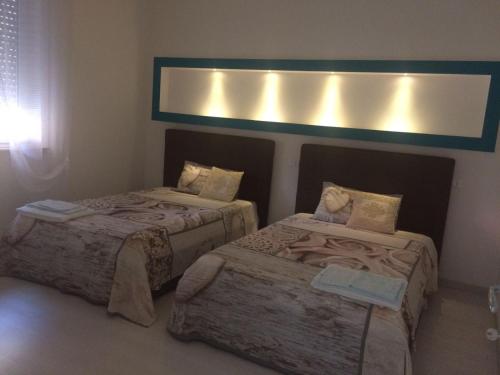 una camera con due letti e una luce sul muro di Smeralda House a Viareggio