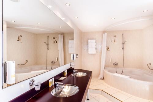 a bathroom with two sinks and a bath tub at Qubus Hotel Legnica in Legnica