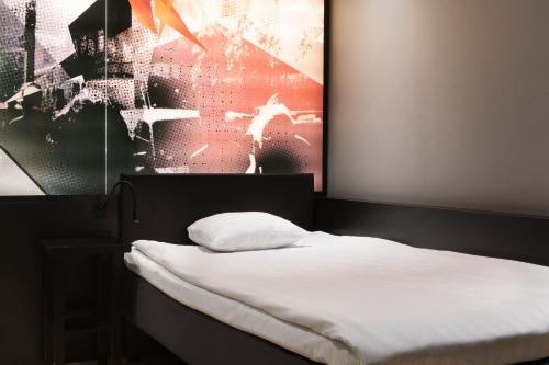 a bedroom with a white bed with a picture on the wall at Comfort Hotel Xpress Stockholm Central in Stockholm