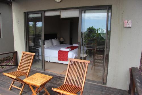 a bedroom with a bed and two chairs on a deck at Baleia Azul 15 in Ponta do Ouro