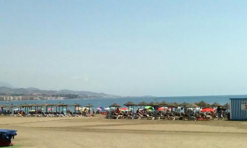 a beach with a bunch of chairs and umbrellas at Las Américas - Mares in Torre del Mar