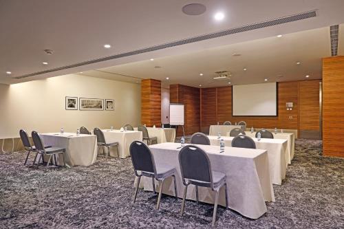 a conference room with tables and chairs and a screen at Warwick Stone 55 Hotel Beirut in Beirut
