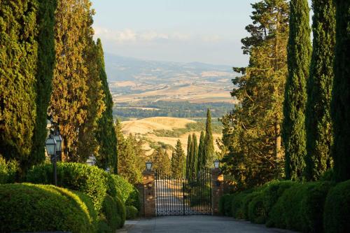 a gate in a garden with trees and a valley at Castello Banfi - Il Borgo in Montalcino