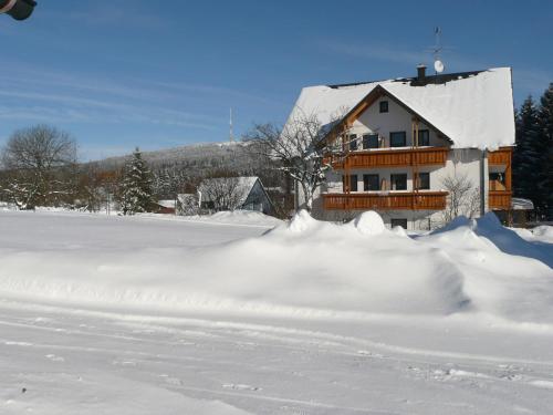 a house with a pile of snow in front of it at Hotel Bergblick in Warmensteinach