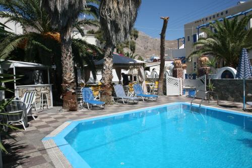 a swimming pool with blue chairs and palm trees at Villa Markos in Perissa