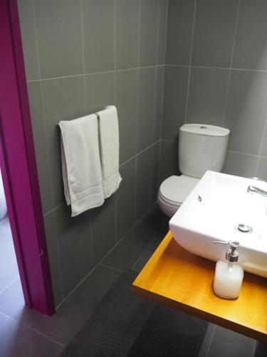 a bathroom with a sink and a toilet and towels at Globo Happy Hostel in Angra do Heroísmo