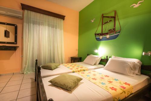two beds in a room with green walls at Elena's Studios in Kalamaki