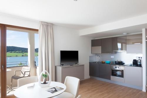 a kitchen and living room with a table and chairs at Hotel Spa Les Rives Sauvages in Malbuisson