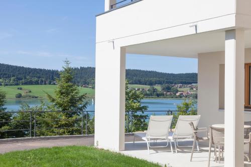 a patio with a table and chairs and a view of a lake at Hotel Spa Les Rives Sauvages in Malbuisson