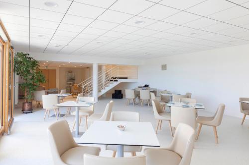 a dining room with tables and chairs and a staircase at Hotel Spa Les Rives Sauvages in Malbuisson