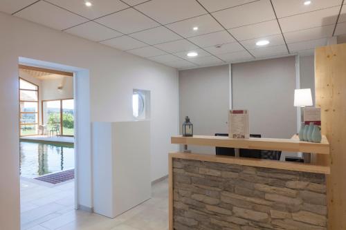 a lobby with a counter and a pool in the background at Hotel Spa Les Rives Sauvages in Malbuisson