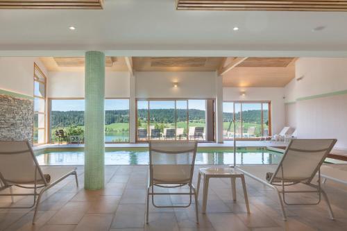 a room with a pool with chairs and a table at Hotel Spa Les Rives Sauvages in Malbuisson