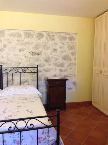 um quarto com uma cama e uma parede de pedra em B&B La Casa Vecchia em Gallo