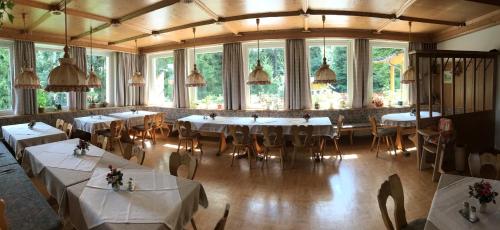 uma sala de jantar com mesas, cadeiras e janelas em Hotel Bergblick em Warmensteinach