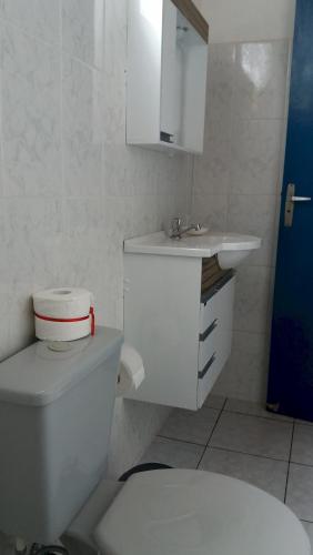 a white bathroom with a toilet and a sink at Pousada Via Maria in Cananéia