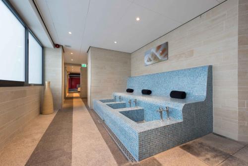 a bathroom with three sinks and a blue tile wall at Htel Serviced Apartments Amstelveen in Amstelveen