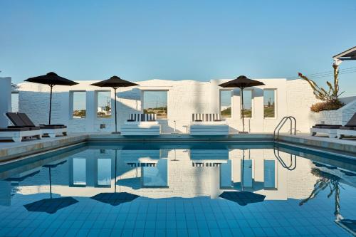 a swimming pool with umbrellas and chairs and a house at Mr and Mrs White Paros in Naousa