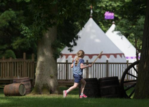 Une jeune fille balançant une batte de baseball dans un parc dans l'établissement Warwick Castle Hotel & Knight's Village, à Warwick