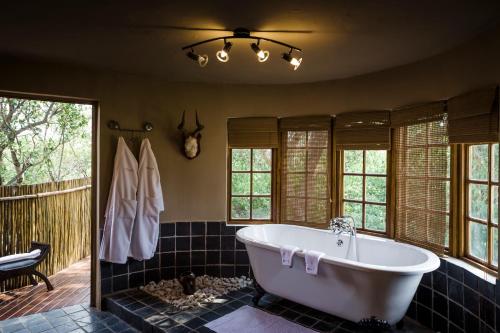 a bath tub in a bathroom with windows at Monate Game Lodge in Modimolle