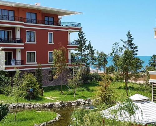 a large red building next to a body of water at Ana's Apartment in Chakvi Oasis in Chakvi