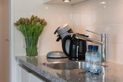 a kitchen counter with a sink and two bottles of water at Htel Serviced Apartments Amstelveen in Amstelveen