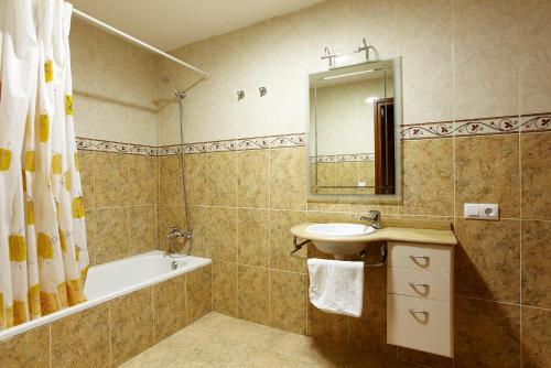 y baño con lavabo, bañera y espejo. en Can Bastons, en Vilanova de la Muga