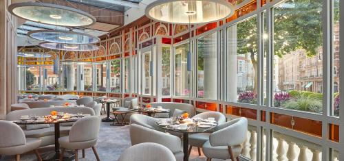 un restaurante con mesas, sillas y ventanas grandes en The Connaught en Londres