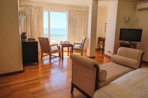 a living room with a couch and chairs and a television at Boa Vista Hotel & Spa - Adults Only in Albufeira