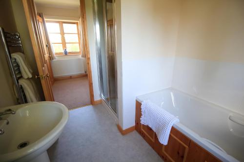 a bathroom with a sink and a toilet and a tub at Three Ways Farmhouse B&B in Stratford-upon-Avon