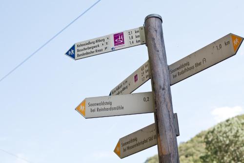 a wooden street sign with directions to different cities at Land-gut-Hotel Forellenhof in Bundenbach