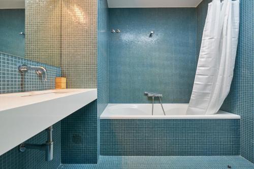 リスボンにあるLuxury Apartment in the most privileged Lisbonの青いタイルの浴槽とシャワー付きのバスルーム