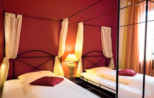 two beds in a bedroom with red walls and a mirror at Hotel 3 Könige in Aachen