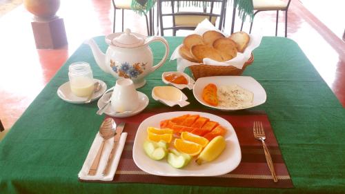 a green table with a plate of fruit and bread at Saubagya Inn in Anuradhapura