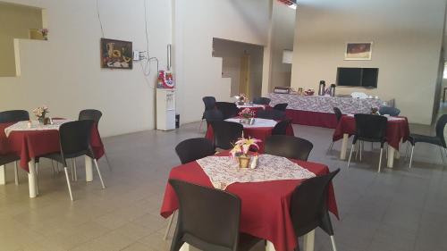 une salle à manger avec des tables, des chaises et un tissu de table rouge dans l'établissement Pousada Portal do Cariri, à Juazeiro do Norte