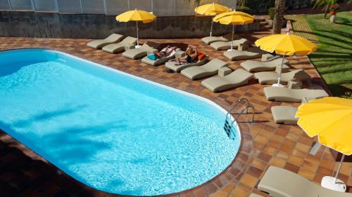 a swimming pool with lounge chairs and umbrellas at Jacarandas Beach in Playa del Ingles