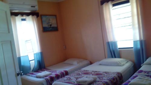 two beds in a small room with two windows at Don Santiago Guesthouse Downtown in San Ignacio