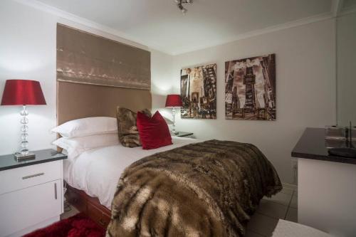a bedroom with a large bed with red pillows at Stylish Gem in Cape Town
