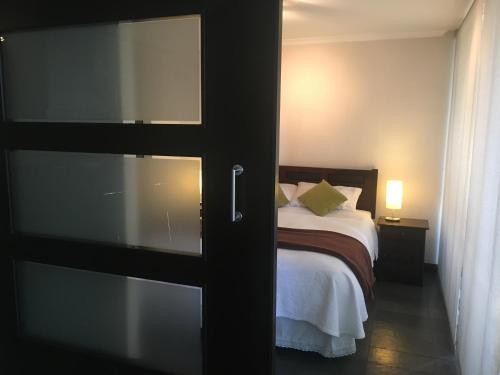 1 dormitorio con 1 cama y puerta corredera de cristal en M Montt Las Condes, en Santiago