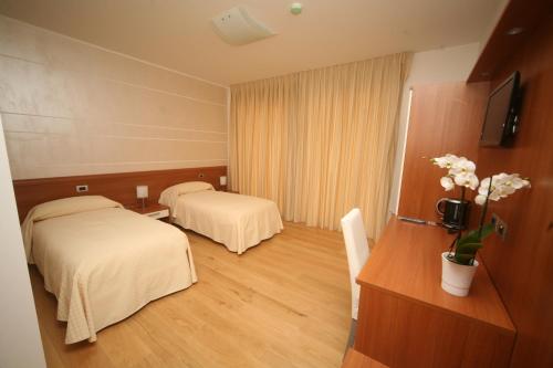 a hotel room with two beds and a television at Resort Monviso in Sanfront