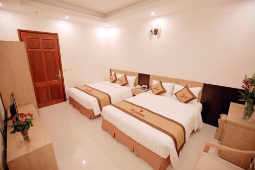 a hotel room with two beds and a door at Anova Airport Hotel - Convenient & Friendly in Noi Bai