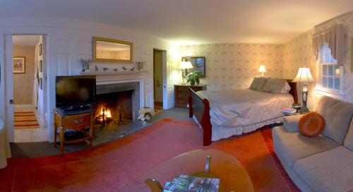 a living room with a bed and a fireplace at Lamb and Lion Inn in Barnstable