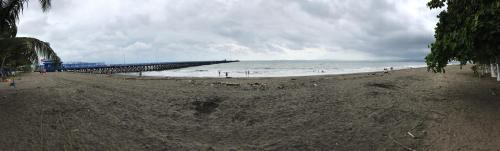 a beach with a pier and people in the water at Hotel Sol Puntarenas in Puntarenas