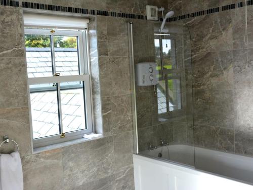 baño con ducha y bañera y ventana en Rivers Bend Cottage, en Skull