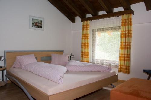 ein Bett in einem Zimmer mit Fenster in der Unterkunft Chasa Val Bella in Samnaun