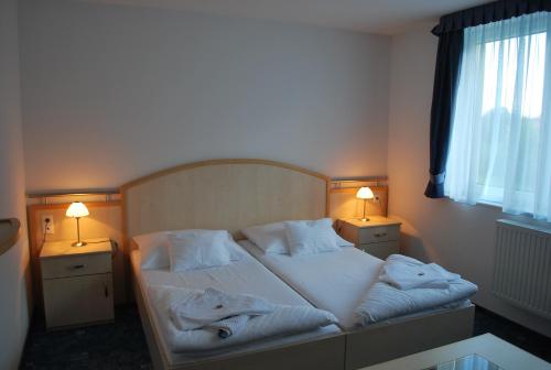 a bedroom with a bed with two lamps on it at Főnix Hotel in Bük