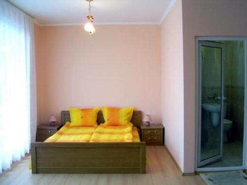 a bedroom with a bed with yellow sheets and a mirror at Family Hotel Velevi in Velingrad