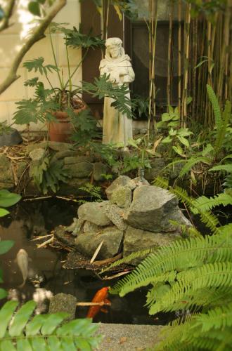 a garden with a statue and some plants at St. Francis Inn - Saint Augustine in Saint Augustine