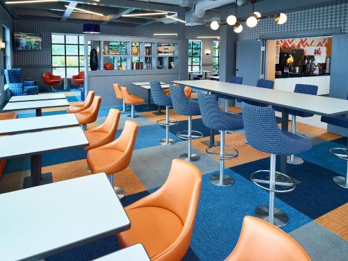 a cafeteria with white tables and chairs and orange chairs at LivINN Hotel Minneapolis South / Burnsville in Burnsville